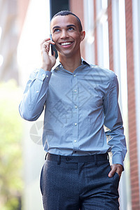 带着手机走出门的笑着微笑的商务人士图片