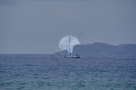 满月在岛和帆船后面升起图片