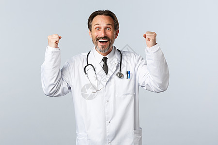 Covid19 冠状病毒爆发 医护人员和流行病概念 松了一口气的快乐男医生收到好消息 举起双手庆祝 满意地微笑 胜利肺炎装备医务图片