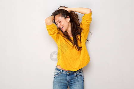 美丽的年轻的年轻女士 用手在灰墙上欢笑的头发图片