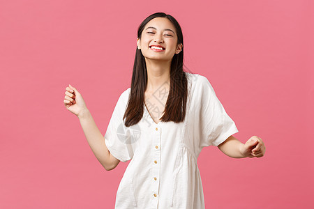 美丽 人们的情绪和夏季休闲概念 无忧无虑的有吸引力的快乐韩国女孩穿着白衣跳舞 欢笑幸福 站在粉红背景上图片