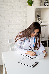 年轻女医生在她的内阁里写作 填充医疗史或阿纳梅尼斯病史诊断护士科学家外科疾病卫生专家病人女士职员图片