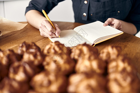 专业女厨师正在现代轻便厨房写食谱配方的秘方糕点女士美食工作糖果商面包职业手工盘子小吃图片