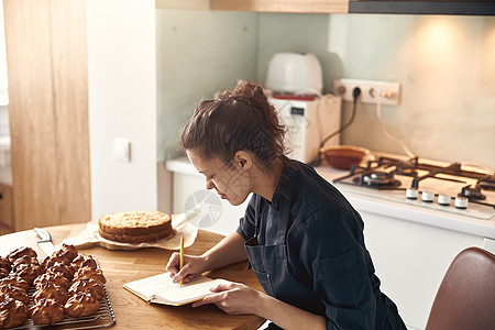 专业女厨师正在现代轻便厨房写食谱配方的秘方面包盘子蛋糕烹饪成人职业糖果商工作面包师糕点图片