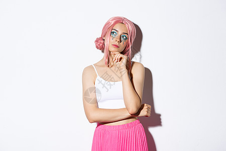 戴着粉红色动漫假发和亮妆的体贴迷人女模特的肖像 看着左上角的横幅 思考 做出选择 站在白色背景上图片