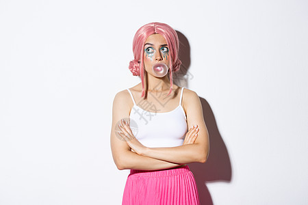 戴着粉红色假发的迷茫派对女孩的形象 浓妆艳抹 吹着泡泡糖 站在白色背景上 在左上角看起来优柔寡断图片