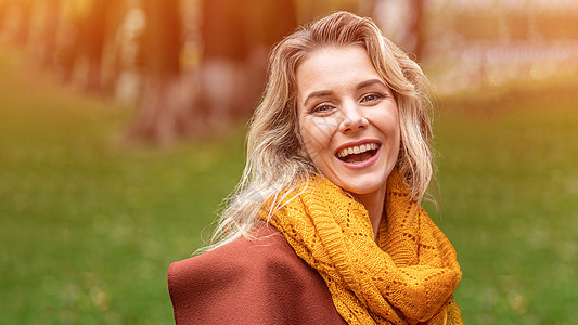 身着秋装和黄色针织围巾的快乐的年轻女子站在秋天的黄色花园或公园里快乐地微笑着 秋叶的美丽的微笑的少妇女孩女性季节头发喜悦闲暇眼睛图片