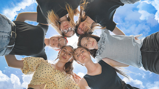 快乐的朋友们拥抱在童话般天空背景的圆圈里伙伴社区耀斑团队女性乐趣拉丁幸福学生男人图片