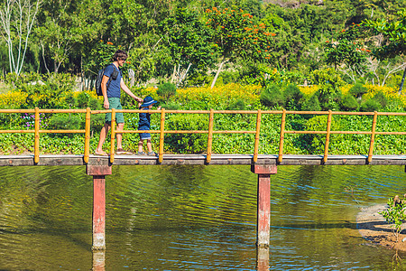 父亲和儿子在水池上沿桥行走 与儿童一起旅行的概念图片