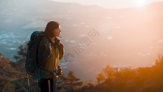 女孩在日落时正在山上攀爬图片