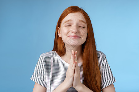 许愿的女孩心底愿意梦想成真双手合十祈祷祈求闭上眼睛微笑真诚的信念愿望实现期待奇迹 站在蓝色背景欢呼女朋友成人快乐学生皮肤女士幸福图片