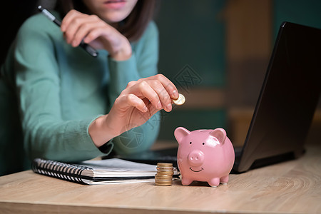 那女孩把她的积蓄放进小猪银行电脑小猪退休预算开支快乐金融经济女士计算器图片