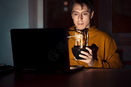 男人在吃面和看电影电影食物学生午餐手表面条电脑笔记本自由职业者技术图片