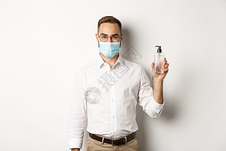 Covid19 社会疏远和隔离概念 身戴医疗面具的雇主展示了手防汗剂 要求在工作中使用抗消毒剂 站在白背景上金融工作室经理广告手图片