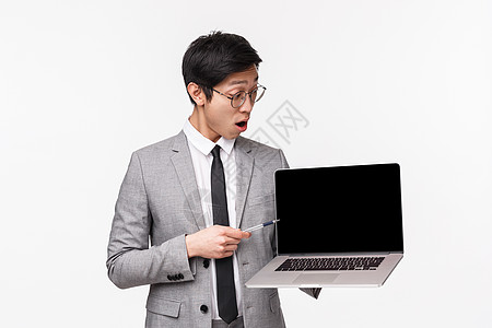 令人印象深刻 兴奋的亚洲男性企业家的腰部肖像 他们惊讶于良好的图表 丰厚的收入 低下巴地看着笔记本电脑显示屏 阅读令人震惊的信息图片