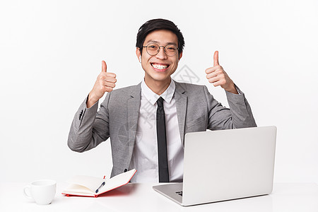 坐在办公桌前 带着笔记本电脑 笔记本 喝咖啡 工作效率高 竖起大拇指 一切都很好 白色背景的亚洲办公室经理的腰上画像图片