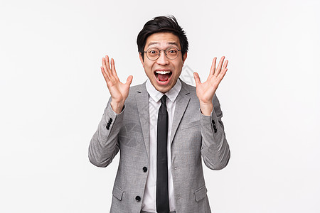 超级快乐的年轻亚洲男办公室经理得到晋升 高薪 听到好消息 反应非常高兴 握手激动 微笑开朗 站在白色背景图片
