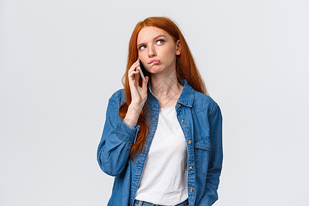 对决定感到困惑 不确定可爱的红头发女人在最喜欢的餐厅点外卖 打电话给某人 看起来很体贴 思考 在说话时思考答案 拿着智能手机图片