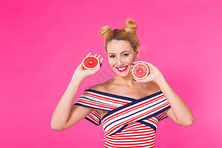 粉红背景的年轻女子手里拿着橙子 笑着笑 色彩迷恋概念 笑声女士皮肤微笑乐趣水果幸福女孩饮食食物快乐图片