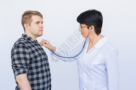 医疗保健 体检 人和医学概念  年轻人和带听诊器的医生在白色背景下听心跳疾病病人检查孩子女性考试成人男人从业者专家图片