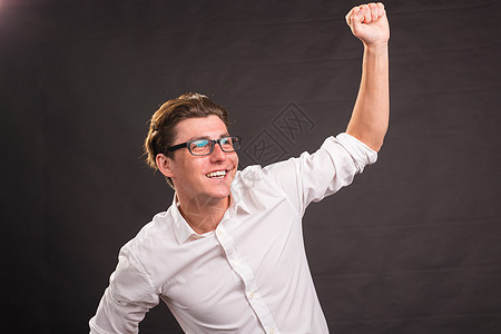 穿白衬衫的帅帅男子 在黑暗背景上表现出获胜的姿势力量微笑喜悦幸福快乐人士胜利衬衫冒充男人图片