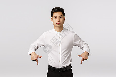 自信 自信 英俊的亚洲男性企业家 表情自信 果断 要求外观和退房 给员工任务 向下指 站立的白色背景图片