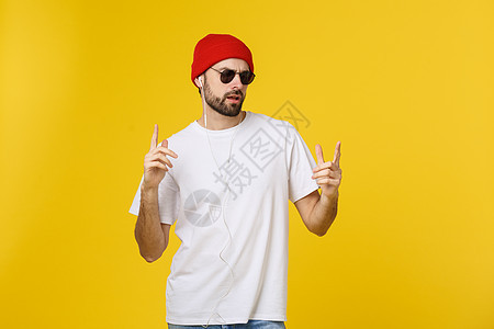 一个英俊年轻男子的肖像 跳舞和听音乐 孤立在黄色背景上衬衫舞蹈工作室喜悦技术乐趣幸福快乐微笑成人图片