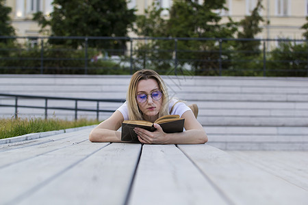 年轻女性嬉皮士在读一本书 在夏天躺在长椅上图片