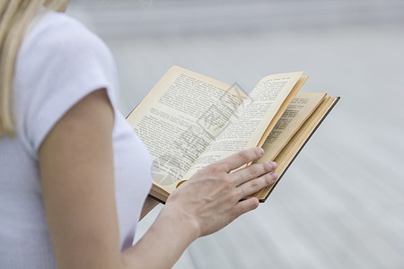 年轻女性手握旧书     户外阅读图片