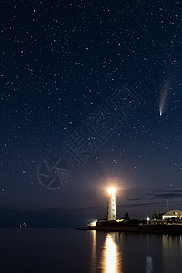 夜晚夜空中白色灯塔上的新彗星的垂直全景性人类发展报告照片图片