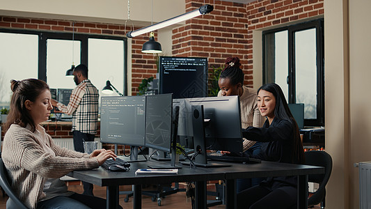 计算机键盘上的软件工程师打字源代码 而同事则坐在办公桌旁图片