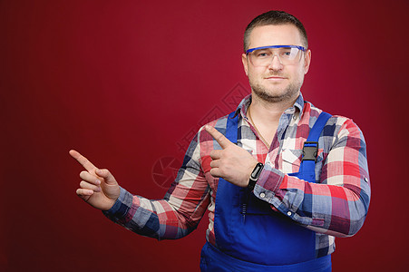 穿着制服和护目镜的迷人白人男性工头将手指指向空白处 工头修理工 master 工作室肖像图片