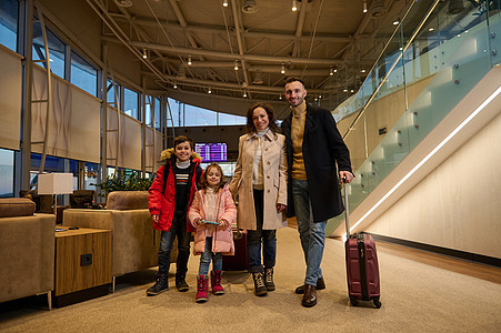 快乐的家庭一起享受旅行 带着行李站在机场出发航站楼的大厅里 等待登机 在信息面板的背景下 有航班时刻表图片