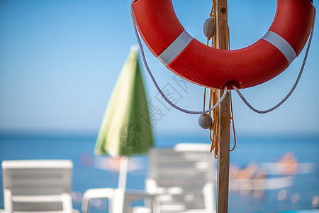 几个白色的太阳休息室和在荒凉海滩上的一个生命浮标 完美的假期概念阳光躺椅天空热带椅子蜜月海岸晴天旅行海岸线图片