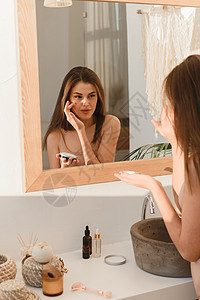 年轻女性在太阳浴时用润湿剂当面施药 每日例行活动 水合和皮肤护理概念脸颊奶油浴室反射润肤皱纹女士身体卫生清洁图片