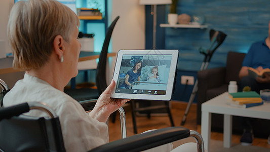 坐在轮椅上的老年人用在线视频电话持有平板电脑图片