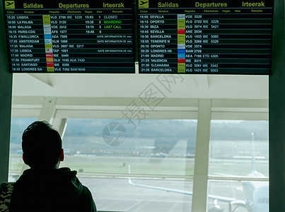一名男子正在查看信息出发板 并在机场检查他的航班 以便在欧洲旅行 乘客在机场航站楼看时间表数字显示 航班延误的游客图片