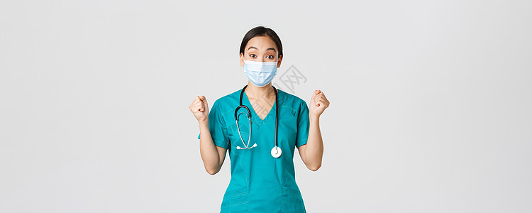 Covid19 冠状病毒病 医护人员的概念 赢得快乐的亚洲女医生 戴医用面具和磨砂膏的医生 看起来乐观 欢欣鼓舞 万岁 白色背景图片