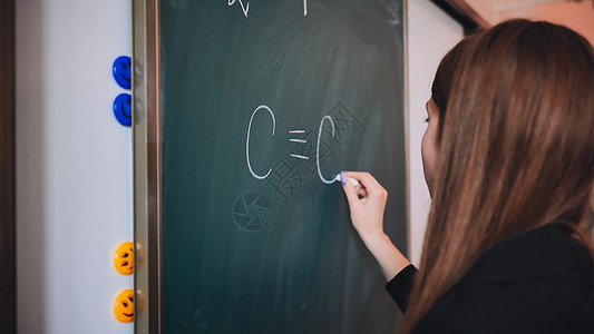 女孩在教室的黑板上写化学配方  是的教育学校生活课堂实验木板化学品家庭作业实验室科学图片