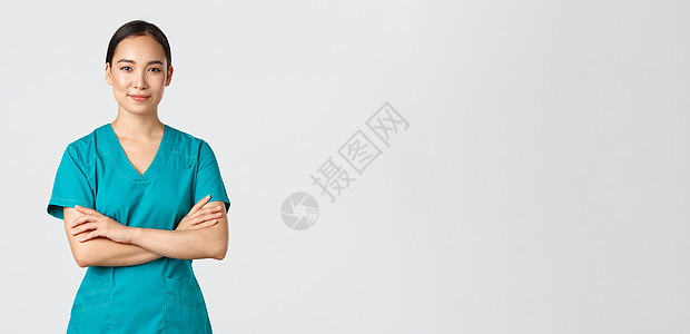 Covid19 医护人员 流行病概念 穿着磨砂服的自信微笑的亚洲护士自信地站着 双臂交叉在胸前 专业医生准备手术 站立白色背景成图片
