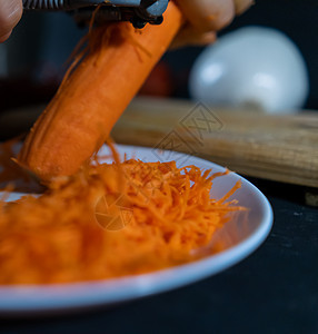 双手剥下薄胡萝卜 将朱丽安的皮刀拔在白板上方橙子食物蔬菜烹饪盘子沙拉饮食营养桌子厨房图片