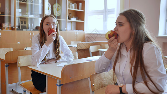 女孩在课间休息时在课堂上吃苹果图片