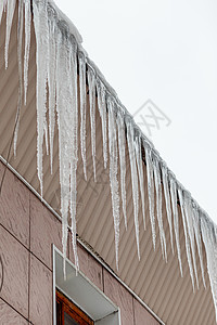 建筑物屋顶上挂着长长的冰柱天空房子窗户阳光外观建筑边缘危险水晶行人图片