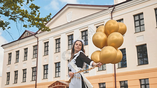 在学校的最后一天 俄罗斯女学生带着气球快乐孩子们教育丝带城市童年乐趣庆典假期钟声街道图片