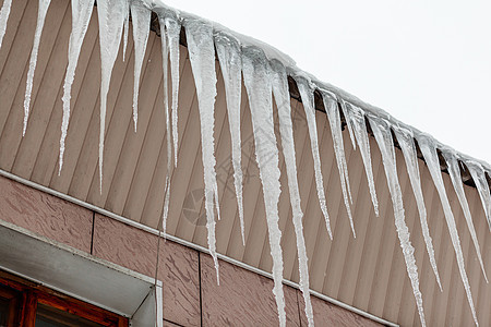 建筑物屋顶上挂着长长的冰柱季节工程风险危险摄影外观阳光行人天空水晶图片