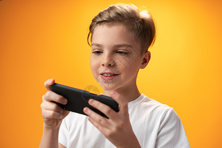 小小孩在黄色背景的智能手机上玩游戏 Name技术游戏孩子们教育孩子微笑男人工具电话屏幕图片