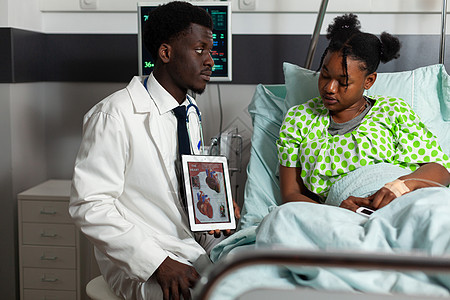 拥有平板电脑的非洲美国医生解释心脏射线摄影学 (计算机)图片