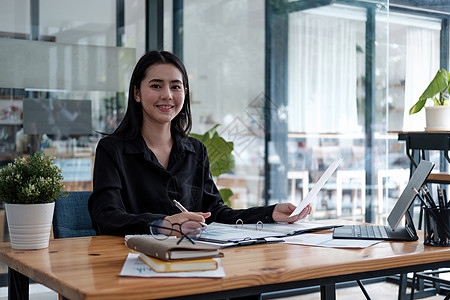 有吸引力的企业家亚洲女性的肖像 女商务人士在使用笔记本电脑从事会计财务工作时看着相机女孩人士职业标志职场经理施工微笑秘书成人图片