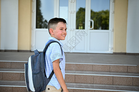 英俊的小学生站在学校大楼前的楼梯上 望着远方看一眼 复制空格图片