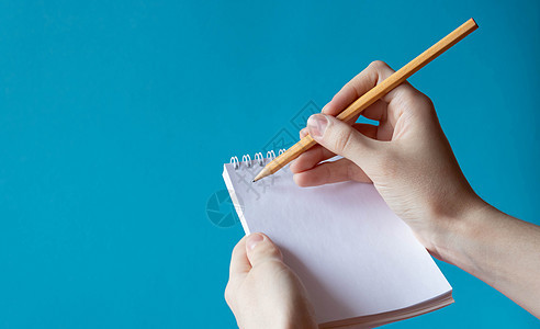 用铅笔手在蓝背景的笔记本中写上笔记本 文本的位置图片